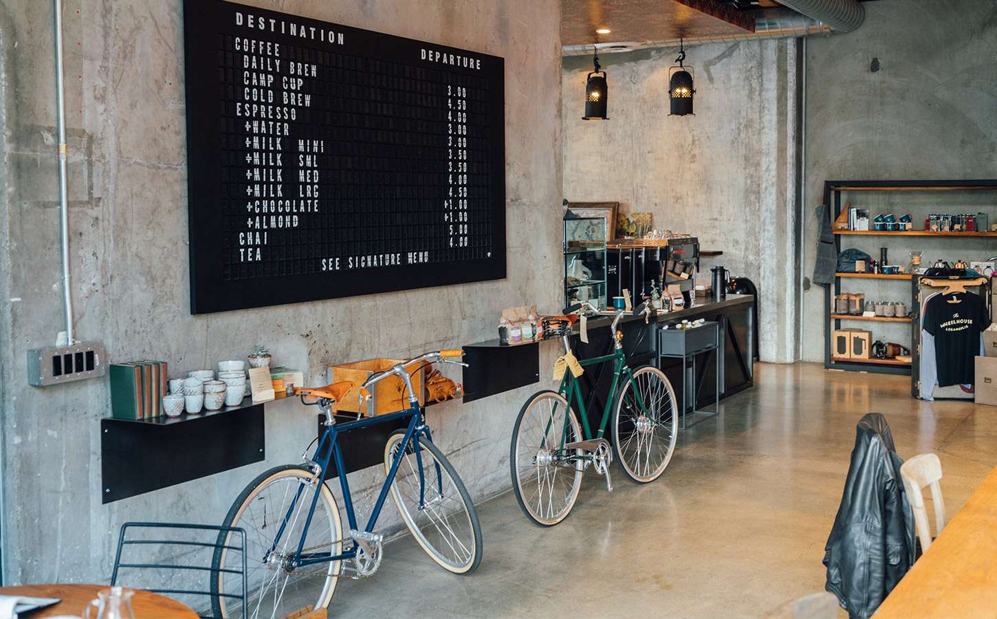 Coffee shop interior with a menu on the wall along with bicycles and mugs.